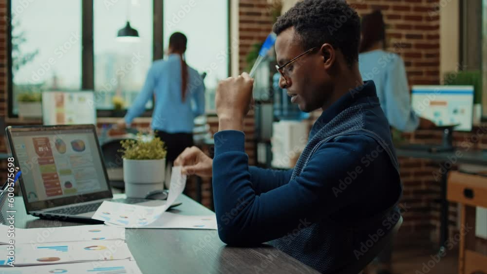 African american man brainstorming ideas to create new business vision, using papers and laptop with statistics to make perfect decision. Company analyst thinking about new research plan in office. African american man brainstorming ideas to create new business vision, using papers and laptop with statistics to make perfect decision. Company analyst thinking about new research plan in office.