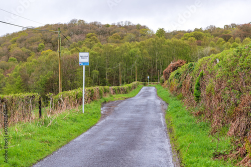 Narrow single lane paved rural road in hills of perthshire scotland with hedge rows and clouds shot in spring above the village of comrie