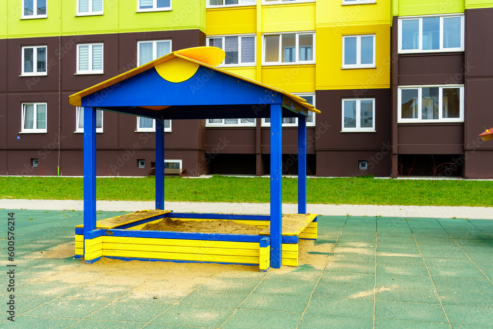 A modern outdoor playground in the courtyard of a building. Colorful children's swings and slides for recreation and games are installed. Playground on the background of residential buildings. A modern outdoor playground in the courtyard of a building. Colorful children's swings and slides for recreation and games are installed. Playground on the background of residential buildings.
