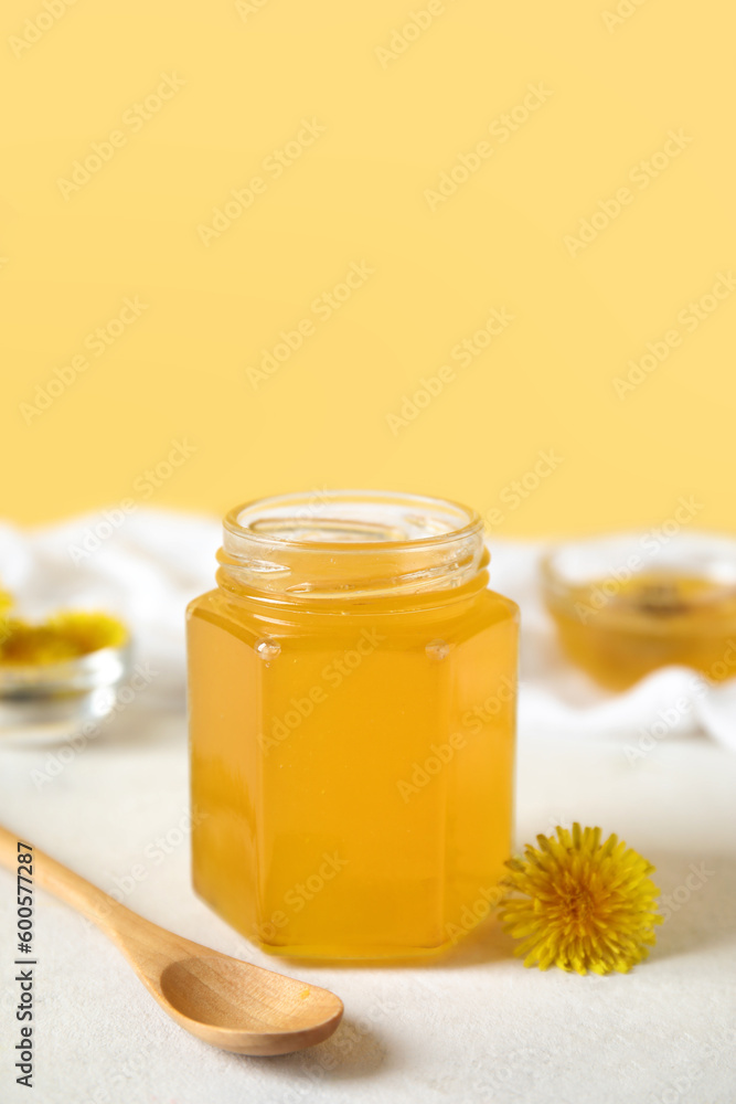 Jar and bowls with dandelion honey on white table Jar and bowls with dandelion honey on white table