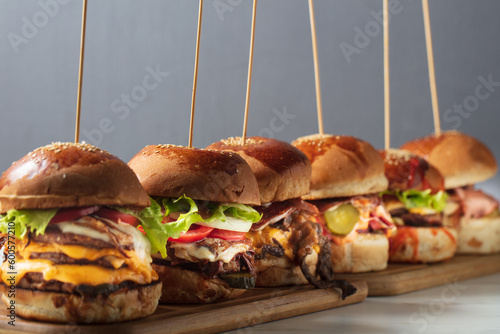 Many different burgers with ingredients on a wood plate. High quality photo