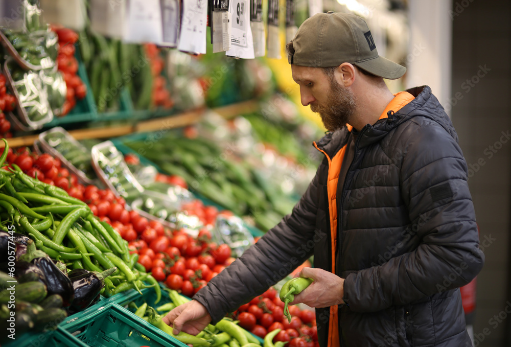 Bearded caucasian man customer selecting green pepper vegetables in supermarket Bearded caucasian man customer selecting green pepper vegetables in supermarket
