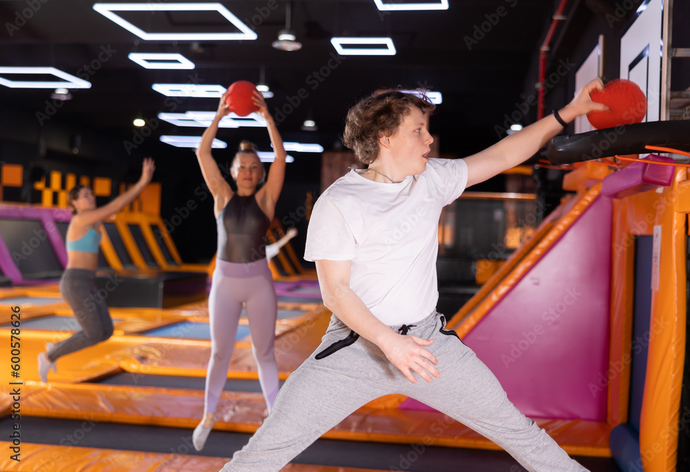 Dynamic teenage boy throwing ball in basket while high jumping in ...
