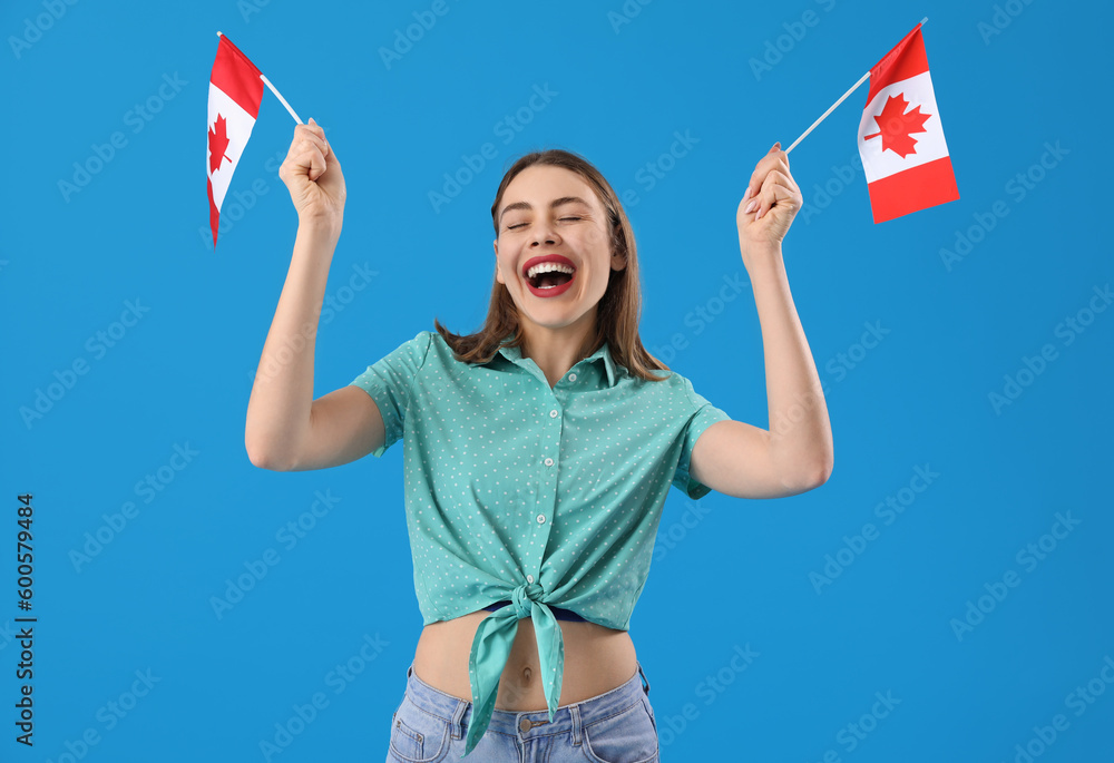 Young woman with flags of Canada on blue background - obrazy, fototapety, plakaty 
