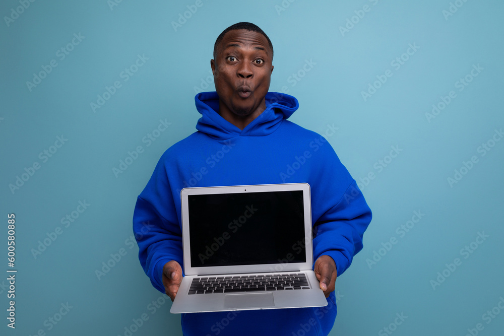 handsome african young consultant in hoodie demonstrating open laptop mockup against background with copy space handsome african young consultant in hoodie demonstrating open laptop mockup against background with copy space
