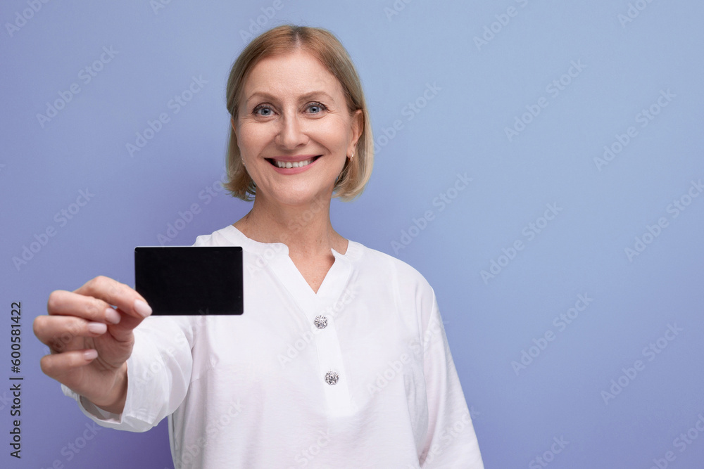 kind pleasant blond mature woman with payment card with mocup on studio background kind pleasant blond mature woman with payment card with mocup on studio background
