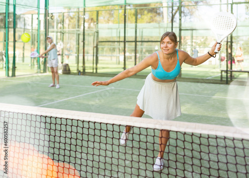 Attractive woman padel tennis player training on court. Young woman using racket to hit ball. © JackF