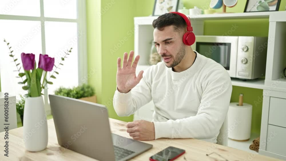 Young hispanic man having video call sitting on table at dinning room Young hispanic man having video call sitting on table at dinning room