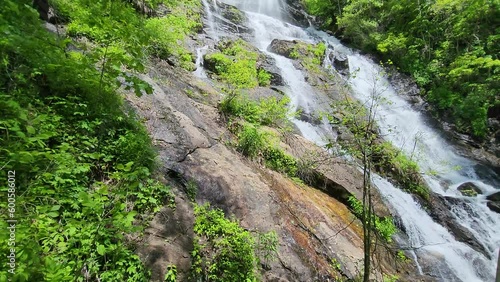 tilt footage of a gorgeous spring landscape with with a flowing waterfall over large rocks surrounded by lush green trees and plants at Amicalola Falls State Park in Dawsonville Georgia USA photo