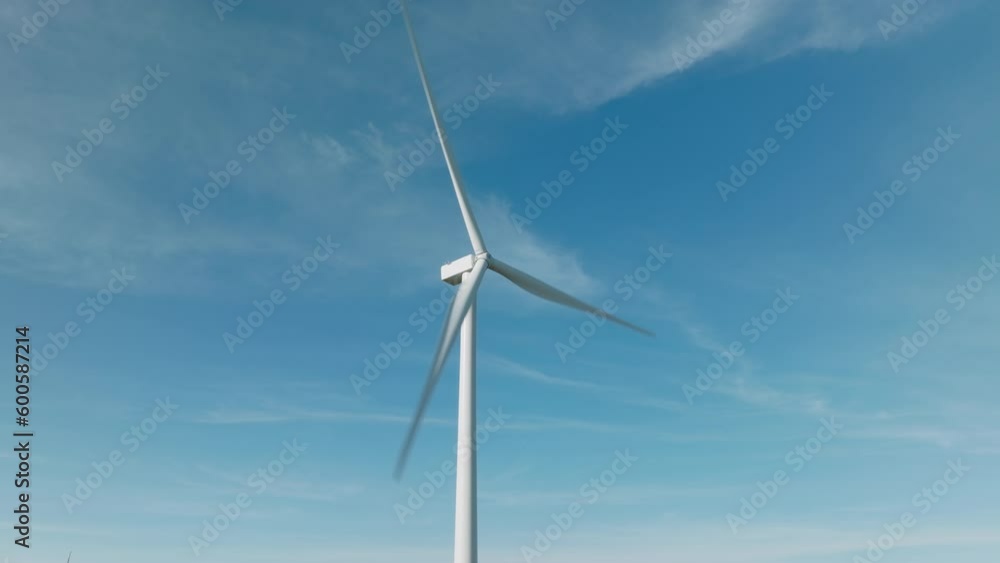 Scenic aerial view of wind turbine on sunny day with perfect clean blue sky and white clouds on background. Wind turbine rotating large rotor blades to generate sustainable electricity power 4K drone Scenic aerial view of wind turbine on sunny day with perfect clean blue sky and white clouds on background. Wind turbine rotating large rotor blades to generate sustainable electricity power 4K drone