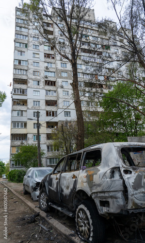 A burnt car with shrapnel holes in front of a house with broken windows after Russia's biggest missile attack on Kyiv, the concept of Russia's war against Ukraine, the genocide of the Ukrainian people photo