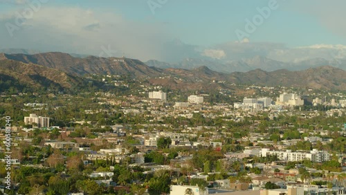 Aerial Panning Shot Of Houses In Suburb Near Hollywood Sign On Mountain, Drone Flying Over Human Settlement Against Sky - Los Angeles, California