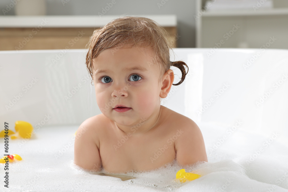 Cute little girl taking foamy bath with rubber ducks at home Cute little girl taking foamy bath with rubber ducks at home