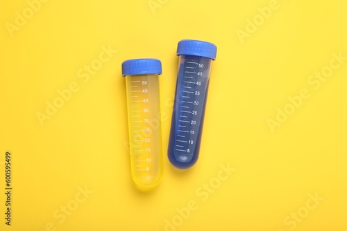 Test tubes with colorful liquids on yellow background, flat lay. Kids chemical experiment set
