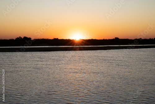 Panorama view of the river under a at sunset. The sun hiding in the horizon. 