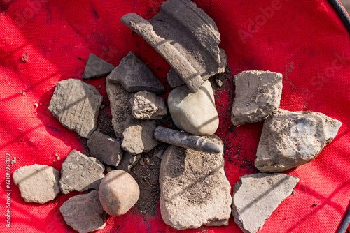 Artifacts found in a field in the ground, stones, ceramics and a modern bullet photo