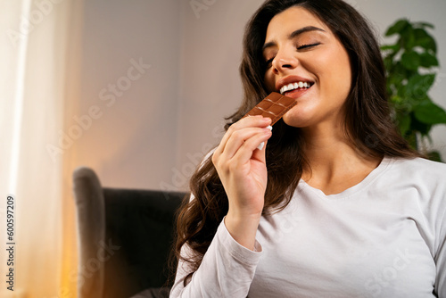 Attractive beautiful long hair girl eating bar of chocolate 