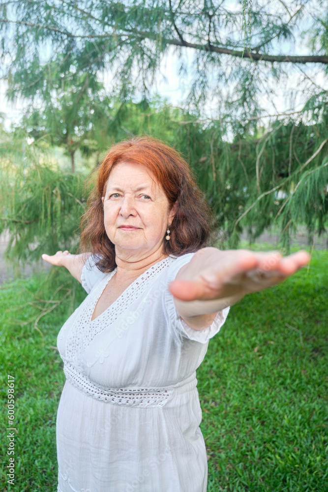 Portrait of a mature Hispanic woman in white clothes practicing yoga outdoors in a park. Concepts: wellness, vitality, active and healthy lifestyle. Portrait of a mature Hispanic woman in white clothes practicing yoga outdoors in a park. Concepts: wellness, vitality, active and healthy lifestyle.