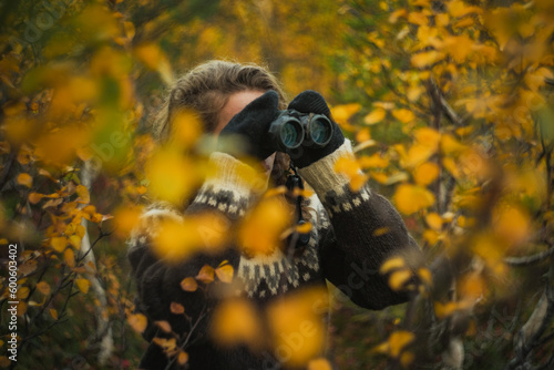 Caucasian woman birdwatching with binoculars autumn forest