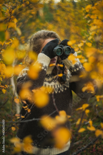 Caucasian woman birdwatching with binoculars autumn forest