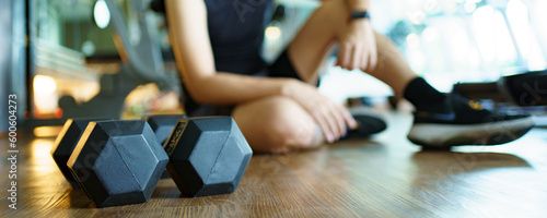 Photography Happy cheerful Asian sportsman relaxing - sitting on the floor after done a weight training exercise in an indoor fitness or gym