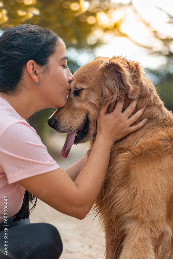 mujer da beso tierno a perro golden retriever sentados alegres, amor, tierno, lengua afuera, mejor amigo del hombre.