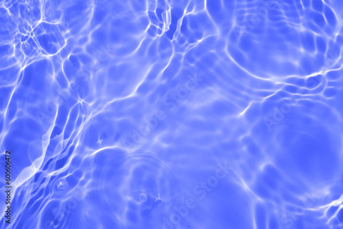 Blue water with ripples on the surface. Defocus blurred transparent blue colored clear calm water surface texture with splashes and bubbles. Water waves with shining pattern texture background.