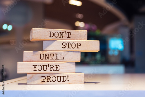 Wooden blocks with words 'Don't stop until you're proud'. Inspirational motivational quote