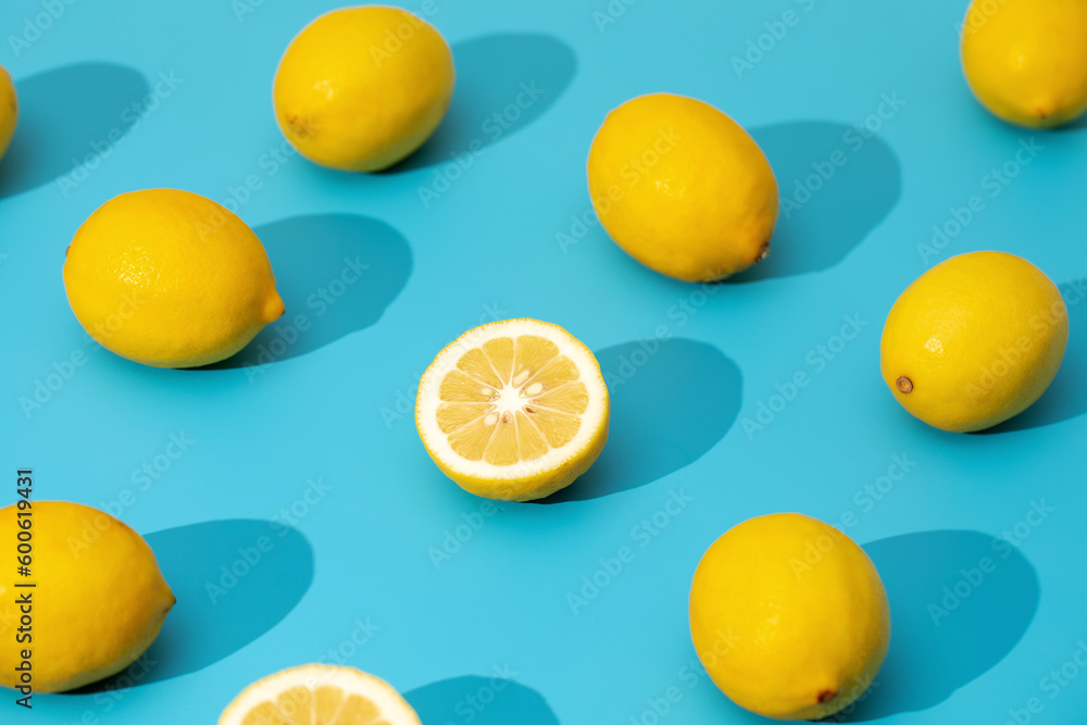 Juicy yellow lemons on a blue background with hard shadows. Summer pattern with ripe lemons. 
