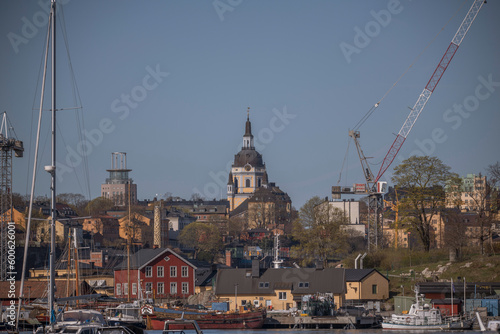 The boat wharf island Beckholmen, buildings and cranes, background the tower of the church Katarina Kyrka and the tower Söder torn, a sunny early tranquil summer day in Stockholm