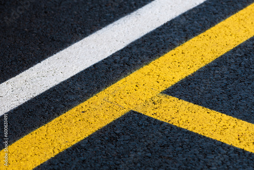 Road marking on brand new asphalt surface of a parking lot, yellow and white lines as abstract background photo