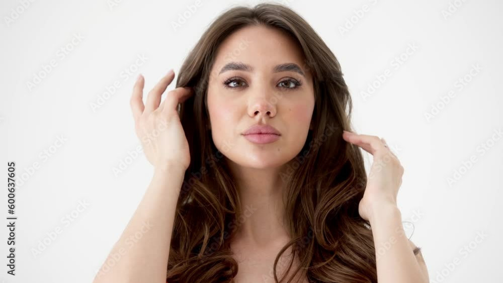 Hair care concept. Close-up portrait of a young pretty woman, pleased with the condition of her hair, looking tenderly at the camera, on a white studio background Hair care concept. Close-up portrait of a young pretty woman, pleased with the condition of her hair, looking tenderly at the camera, on a white studio background