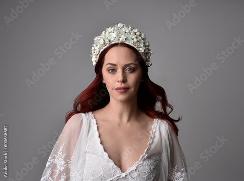 Close up portrait of beautiful red-haired female model wearing an pearl jewelled crown headdress. , isolated on a studio background.