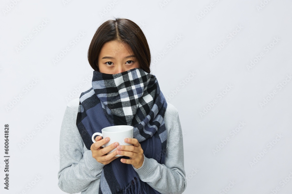 Asian woman cold flu holding a mug of tea in plaid with fever is sick from the virus on a white background Asian woman cold flu holding a mug of tea in plaid with fever is sick from the virus on a white background