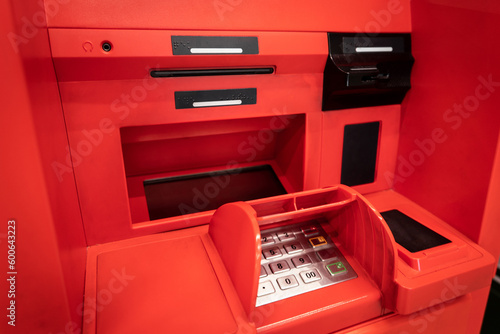 Working area of a red ATM with a keyboard, a card reader and a bill dispenser.