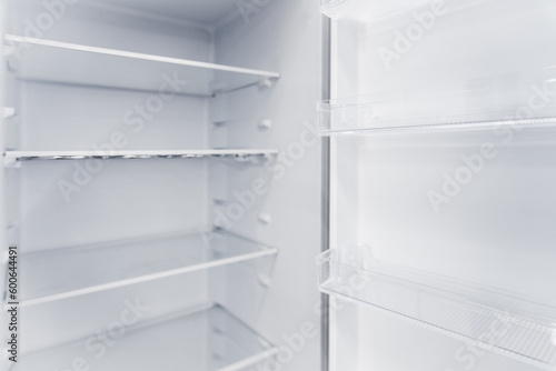 Empty white vertical new home refrigerator with shelves.
