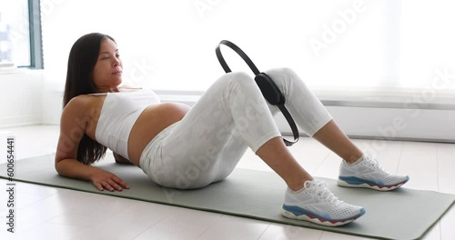 Prenatal exercises. Pregnant woman training doing pelvic exercise and thigh workout lying down on yoga mat. Portrait of expectant mother and pregnancy belly doing bodyweight training at home photo