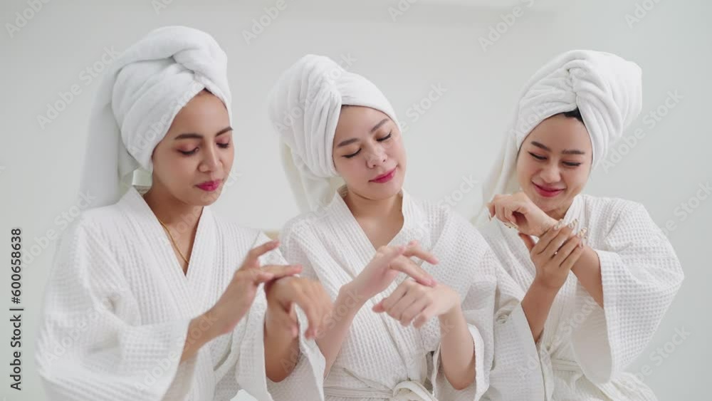 Group of young beautiful Asian woman in white bathrobe enjoy applies moisturizing cream to skin feeling fragrant smell. Skin care concepts Group of young beautiful Asian woman in white bathrobe enjoy applies moisturizing cream to skin feeling fragrant smell. Skin care concepts