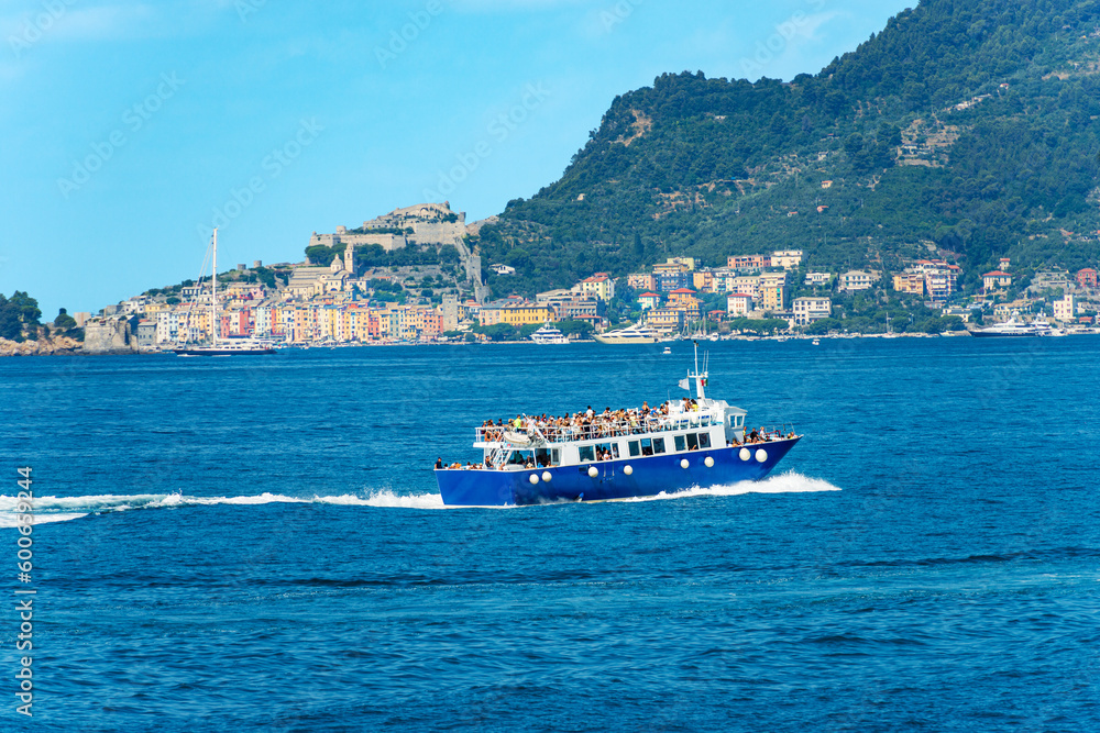 Tour boat or ferry with many tourists in motion in the Gulf of La Spezia to the Cinque Terre, Porto Venere or Portovenere town and Palmaria island, Liguria, Italy, Europe.