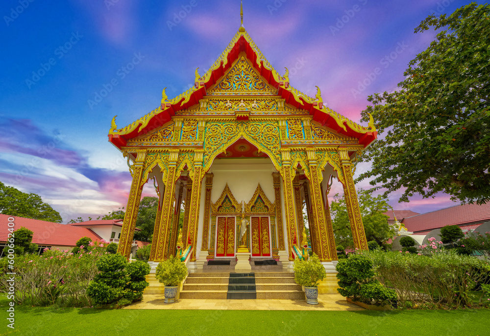 Beautiful Wat Buddhist temple in Phuket Karon Thailand. Decorated in beautiful ornate colours of Gold blue green red and White. Sunset Sunrise lovely sky and cloud colours