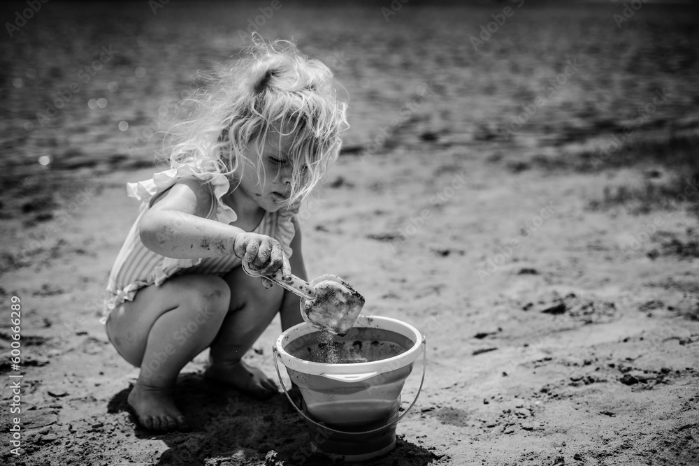 Messy child playing in sand on beach with bucket and shovel Stock Photo ...