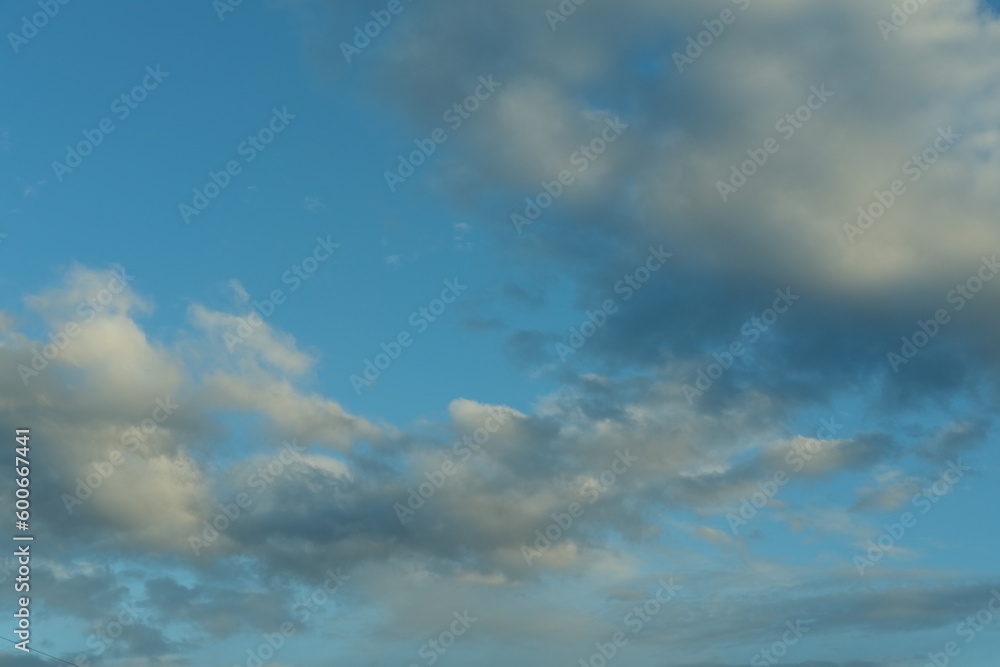 Blue sky background with white fluffy cumulus clouds. Panorama of white fluffy clouds in the blue sky Blue sky background with white fluffy cumulus clouds. Panorama of white fluffy clouds in the blue sky