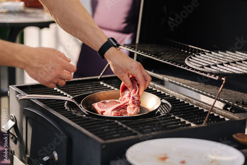 Male hand put T-bone Steak on a heated pan. Man grilling steak on carbon steel pan. French cuisine. BBQ concept
