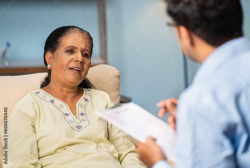Obraz premium Indian senior woman explaining problems to psychologist during counselling at home - concept of home appointment, troube assessment and mental illness