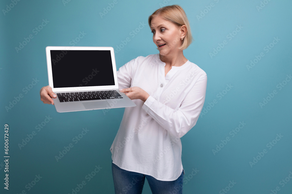 successful 50s middle aged woman with blond hair demonstrates a laptop with mocup successful 50s middle aged woman with blond hair demonstrates a laptop with mocup