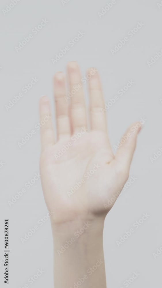 Vertical video. Hello gesture. Greeting sign. Woman waving hand on light background. Vertical video. Hello gesture. Greeting sign. Woman waving hand on light background.