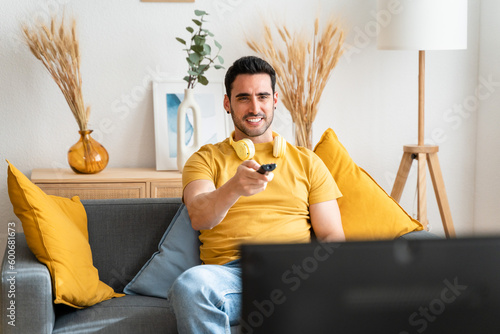 Young man sitting on sofa watching TV.