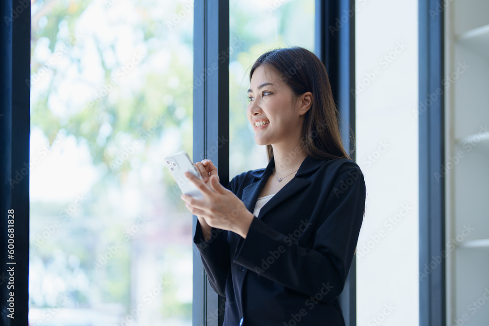 Asian businesswoman in office happy and cheerful during using smartphone and working. Female employees express the excitement of success and bonuses. Asian businesswoman in office happy and cheerful during using smartphone and working. Female employees express the excitement of success and bonuses.