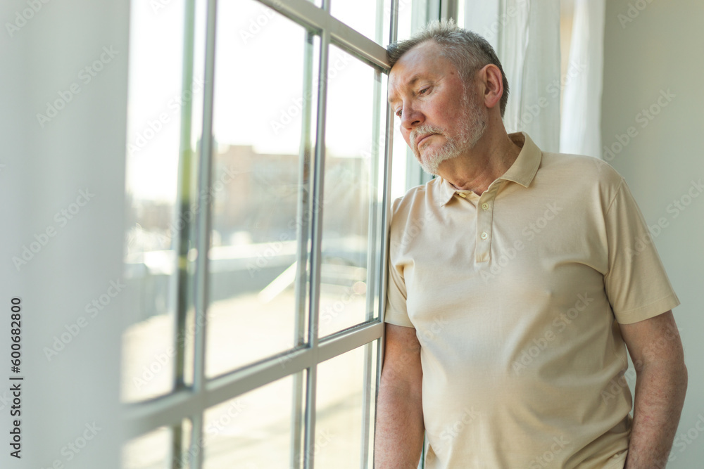 Sad tired lonely disappointed older senior man at home alone. Unhappy grandfather looking sadly outside window experiencing grief relative death bad news. Stressed elder man suffering from loneliness Sad tired lonely disappointed older senior man at home alone. Unhappy grandfather looking sadly outside window experiencing grief relative death bad news. Stressed elder man suffering from loneliness
