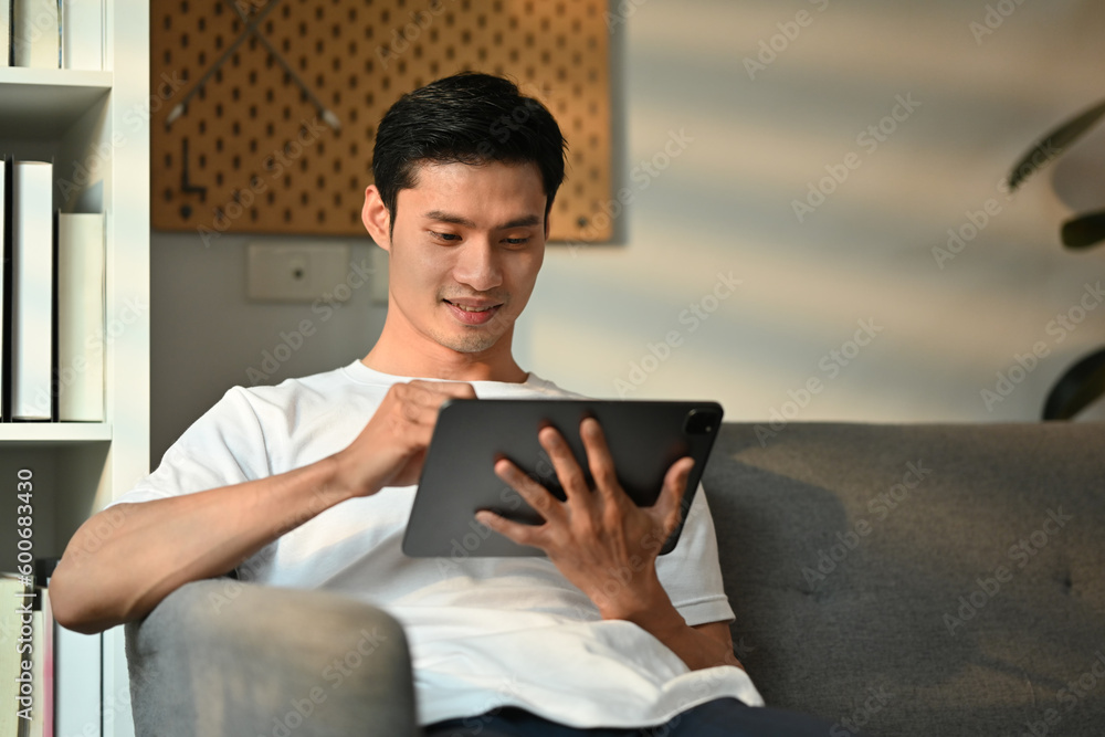 Handsome man freelancer sitting onsofa and using digital tablet. Communication, people, technology concept